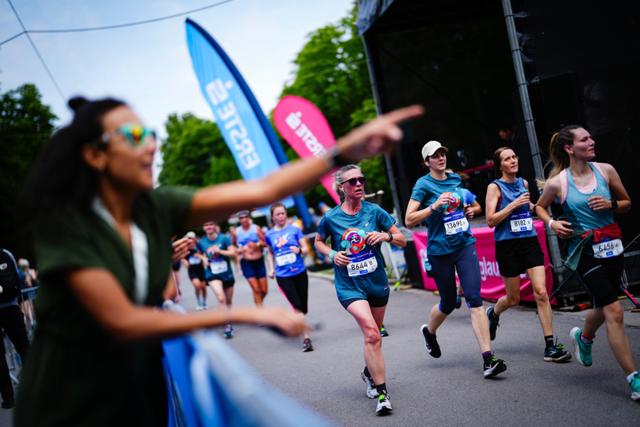 A group of runners participating in a race, with a spectator in the foreground enthusiastically pointing and cheering them on © Eva Manhart, All rights reserved