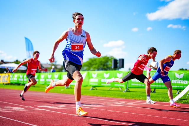 A group of athletes sprinting on a track, with one runner in the lead crossing the finish line © Eva Manhart, All rights reserved