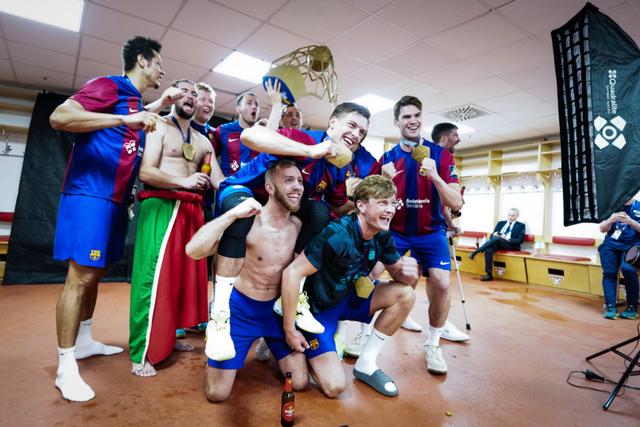 A group of jubilant soccer players in a locker room, some shirtless, celebrating with a trophy © Eva Manhart, All rights reserved