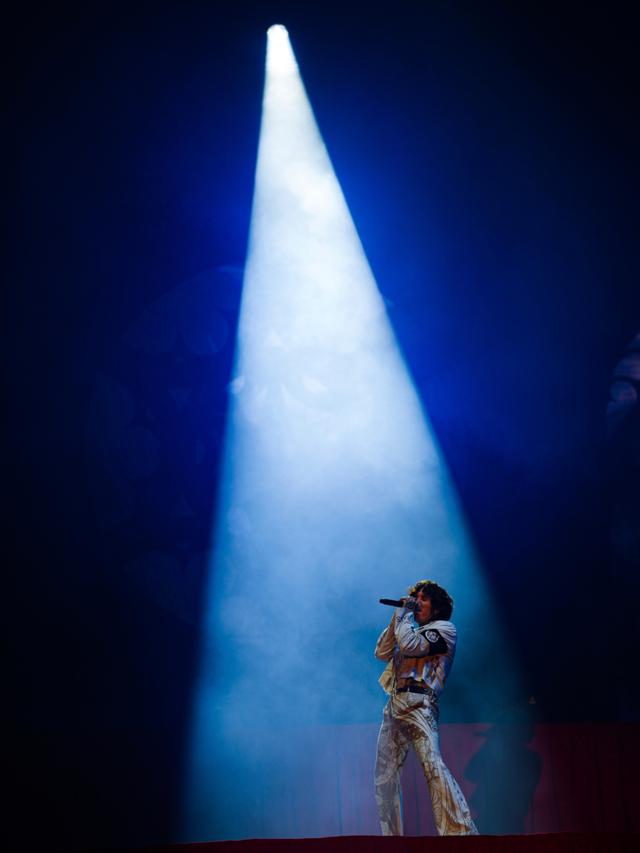 Oliver Sykes stands on stage under a bright spotlight, singing into a microphone