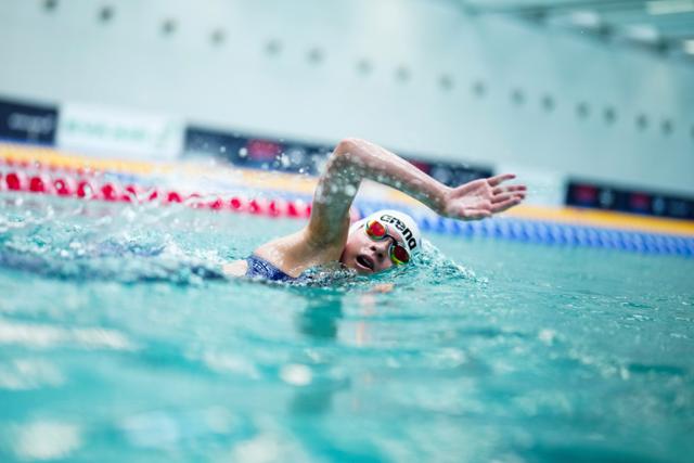 A young swimmer performing the front crawl in an indoor pool