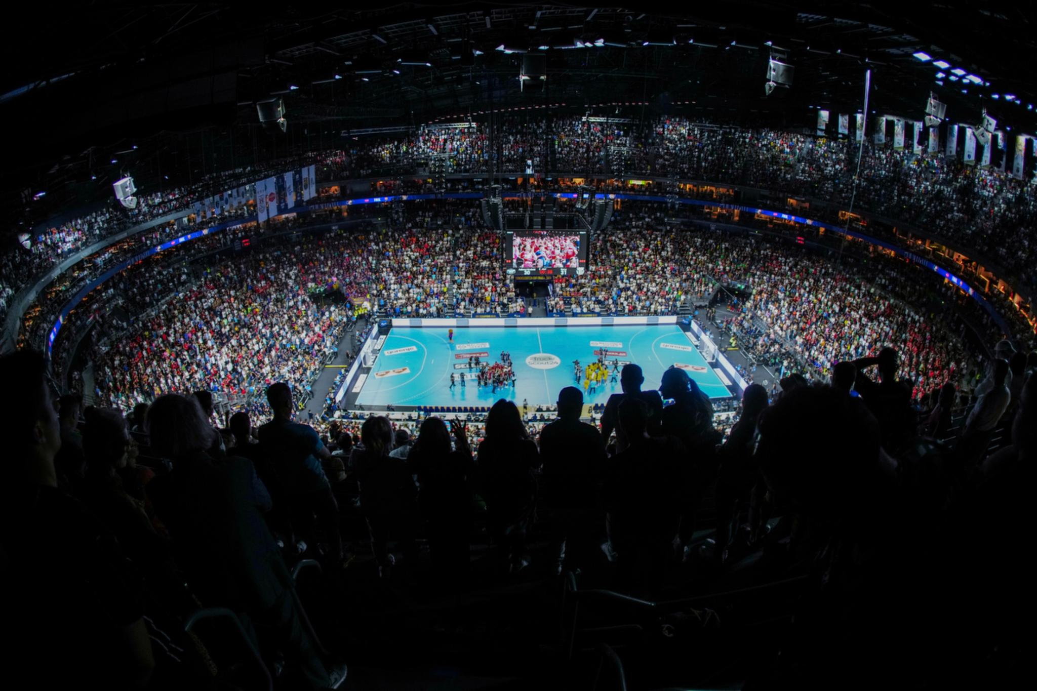 A large indoor sports arena filled with spectators, with a brightly lit central court and players in action © Eva Manhart, All rights reserved